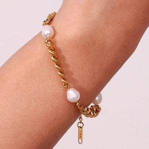 Detailed macro view of gold-plated twisted chain bracelet with baroque pearls and 18K tag