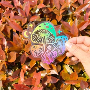 Detail of mushroom suncatcher window sticker with rainbow prism film on red leaf background