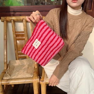 Detail of red and pink striped plush makeup bag with 'Boutique beauty' patch in hand
