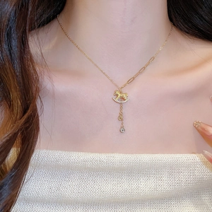 Detail of gold plated rocking horse pendant necklace with crystal accents and layered chain