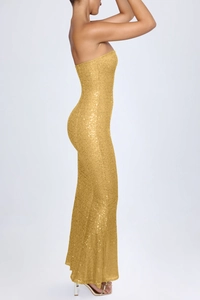 Detail of elegant gold sequined evening gown showing shimmering texture and long floor-length hem