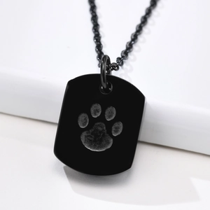 Macro view of black stainless steel rectangle pendant with engraved dog paw print