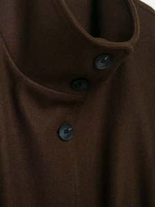 Close-up of a high collar dark brown wool coat with three black buttons detail