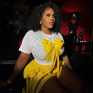 Détail du t-shirt blanc avec grand nœud jaune et jupe en dentelle à franges