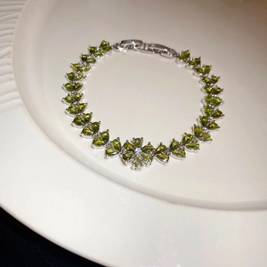 Macro shot of emerald flower bracelet with teardrop gemstones on a ceramic tray