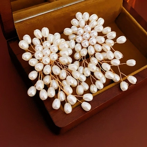 Détail macro de boucles d'oreilles perles et fleurs dans un écrin à bijoux en bois
