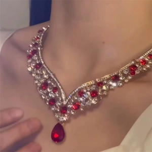 Detail of a vintage V-shaped gold necklace with red pear-cut zircon and white crystals