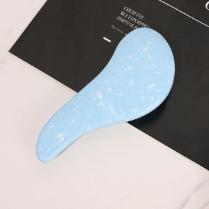 Blue marble ergonomic massage hairbrush for detangling hair on professional studio background