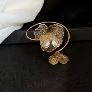 Detailed shot of a gold open cuff bracelet featuring hollow floral designs with crystals
