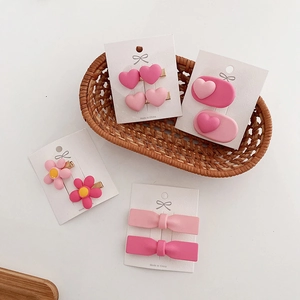 Detailed close-up of pink heart and bow hair clips on a card in a woven basket