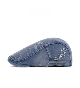 Detail of blue denim flat cap showing washed texture, lattice pattern, and metal buckle