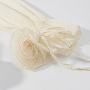 Macro shot of off-white chiffon fabric with 3D rose floral details and pleated texture
