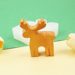 DIY Christmas elk silicone mold with finished golden resin reindeer decor on green background