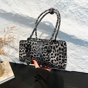 Rectangle handbag with leopard print and thin shoulder strap shown in a hand-held pose
