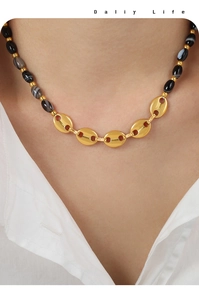Détail du collier fermoir grain de café avec perles d'agate sur chemise blanche