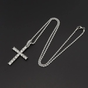 Detailed close-up of a silver-toned tennis chain with a sparkling crystal cross pendant