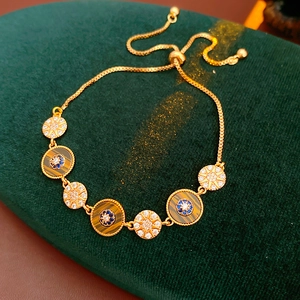 Detail of gold adjustable bracelet with starburst and blue zircon charms on green velvet