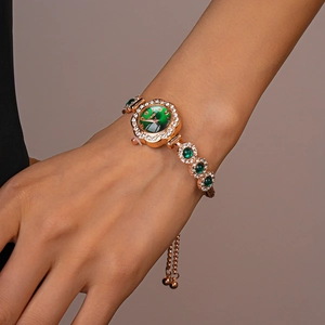 Detail of rose gold rhinestone watch featuring a vintage green dial and floral bezel