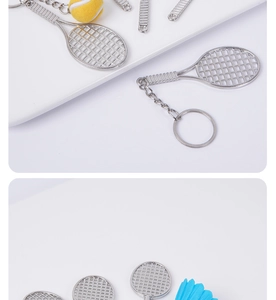 Close-up of mini silver metal tennis and badminton racket keychains on white surface