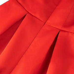 Close-up of red pleated fabric with detailed stitching and vibrant satin finish