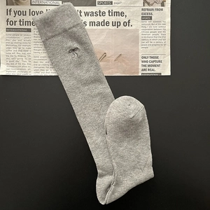 Detail of grey knitted knee-high socks featuring delicate bow embroidery and soft texture