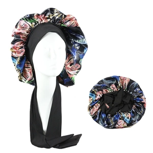 Detail of satin sleep bonnet featuring vibrant tropical floral print and black elastic tie
