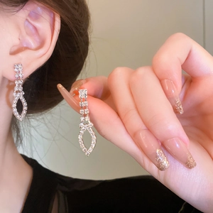 Close-up of dangling silver tassel earrings with sparkling crystals worn by a model
