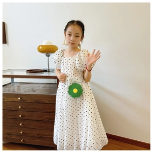 Detail of green flower-shaped crossbody bag paired with a white polka dot puff sleeve dress