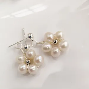 Macro shot of minimalist handmade flower stud earrings with five white freshwater pearls