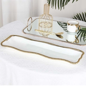 Macro detail of rectangle white ceramic plate with gold beaded trim in elegant setting