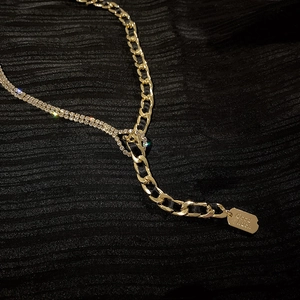 Collier chaîne asymétrique doré avec strass et fermoir cœur sur fond noir
