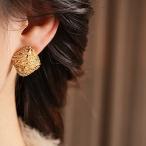 Detailed close-up of a model wearing a gold square earring with pavé-set cubic zirconia