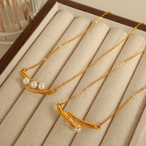 Élégant collier de gousse de pois dorée avec trois perles blanches sur boîte à bijoux