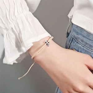 Detail eines cremefarbenen gewebten Seilarmbands mit süßem Panda-Anhänger am Handgelenk