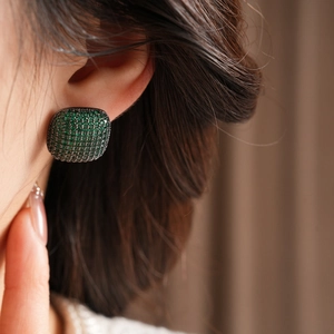 Macro detail of vintage emerald green square stud earrings on female model