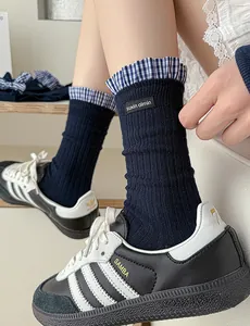 Detail of navy blue crew socks featuring plaid lace trim and vertical ribbed knit texture