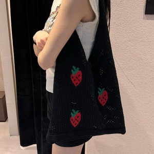 Borsa tote in maglia nera con motivo a fragole rosse portata a spalla per uno stile casual