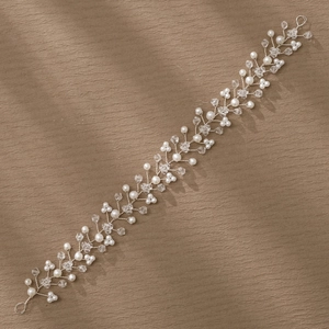 Detailed view of handmade bridal headband with white pearls and silver wire on brown fabric
