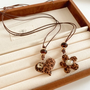 Détail de pendentifs cœur et fleur en résine léopard avec cristaux sur cordon marron