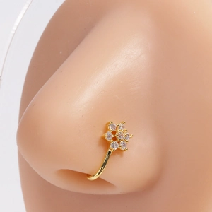 Vue macro d'un faux piercing de nez en fleur dorée serti de zircons porté par un mannequin