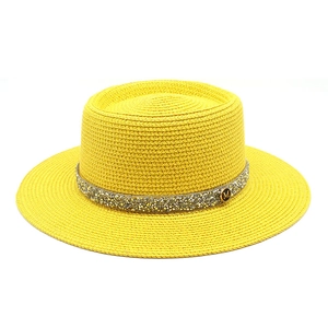 Close-up of woven yellow boater hat with shimmering rhinestone band and metal M logo