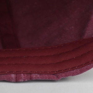 Close-up of wine red cotton twill fabric with triple-stitched seams and frayed edges