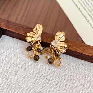 Golden butterfly earrings with tiger eye stone and crystal tassels on linen background