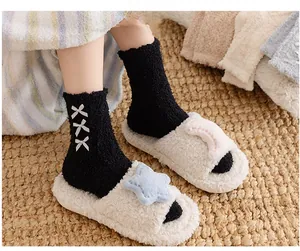 Close-up of black coral fleece socks with white bows and plush slippers in home setting