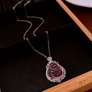 Pink Buddha pendant necklace with zircon flower details on high-end wood display