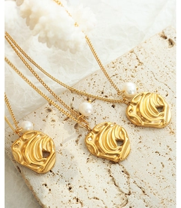 Detailed view of irregular gold pendants with freshwater pearls on a natural stone base