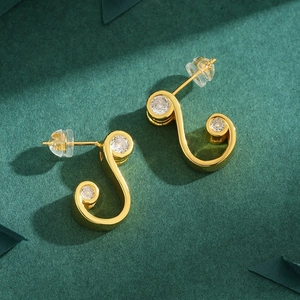Elegant gold music note earrings with sparkling zircon stones on a deep green backdrop