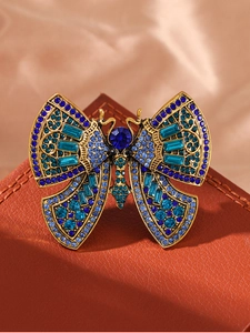 Macro shot of gold butterfly brooch with blue rhinestones on leather background