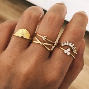 Detailed close-up of stacked gold rings featuring sunrays, crescent moon, and crown designs