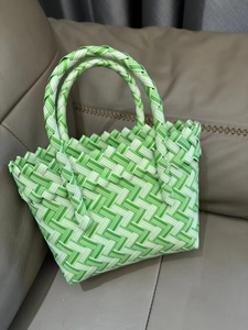 Detail of green and white striped handmade woven tote basket placed on a sofa